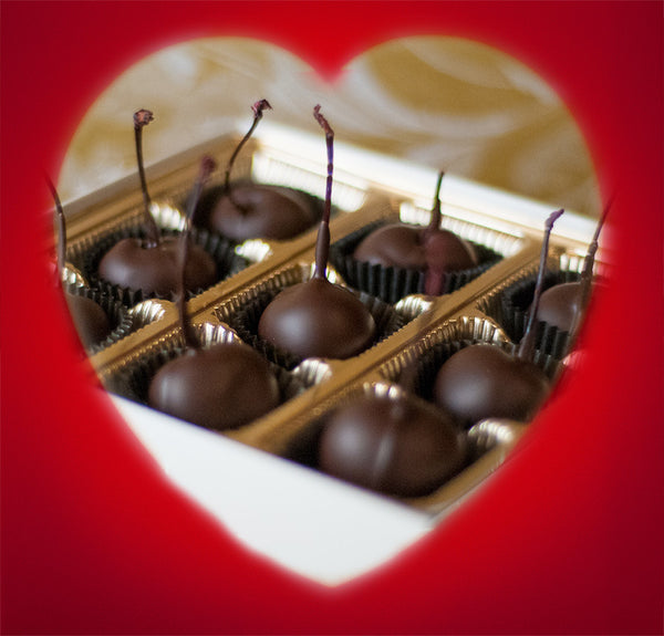 Valentine's Chocolate Cherries — box of stem-on chocolate-covered cherries viewed through a red heart-shaped cutout.