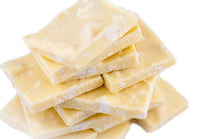 Stack of White Chocolate Toasted Macadamia Bark squares with macadamia nut pieces visible throughout the white chocolate.
