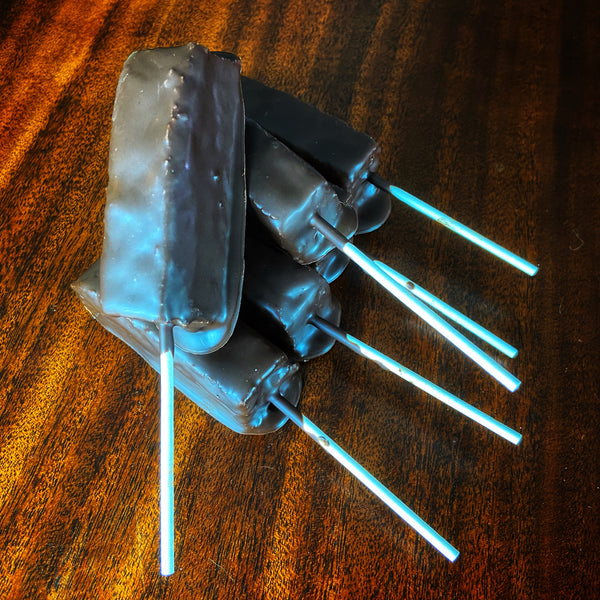 Brownie Pop base — stack of bare chocolate-coated brownie pops on sticks before decoration.