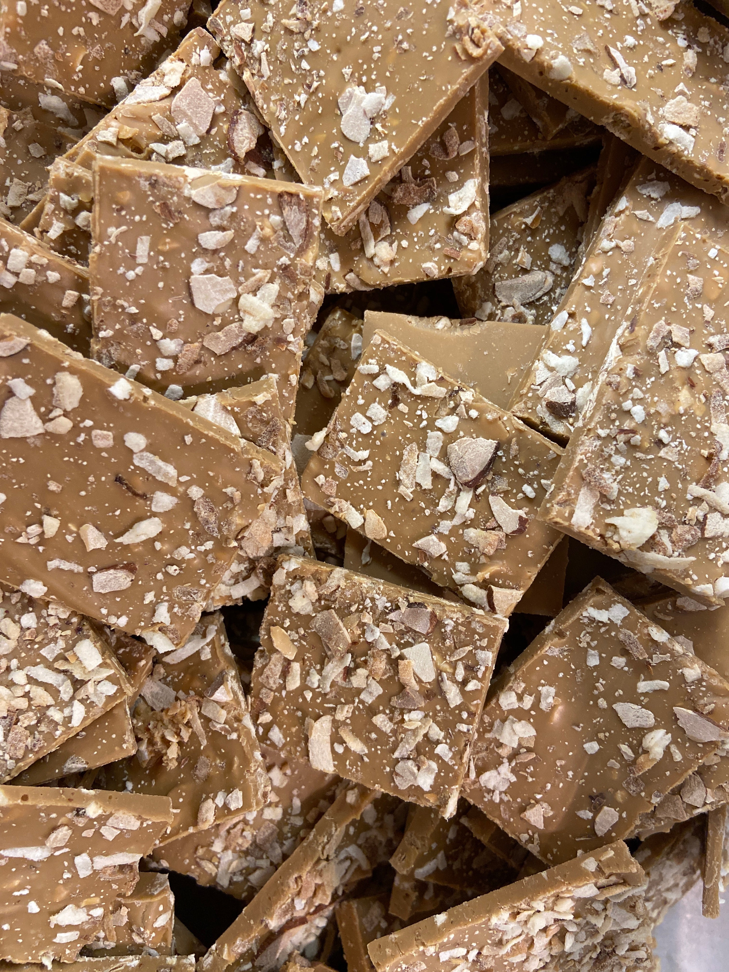 Island Time Bark — chocolate bark broken into rough squares with crushed nuts and coconut flakes embedded throughout.