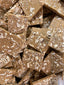 Island Time Bark — chocolate bark broken into rough squares with crushed nuts and coconut flakes embedded throughout.