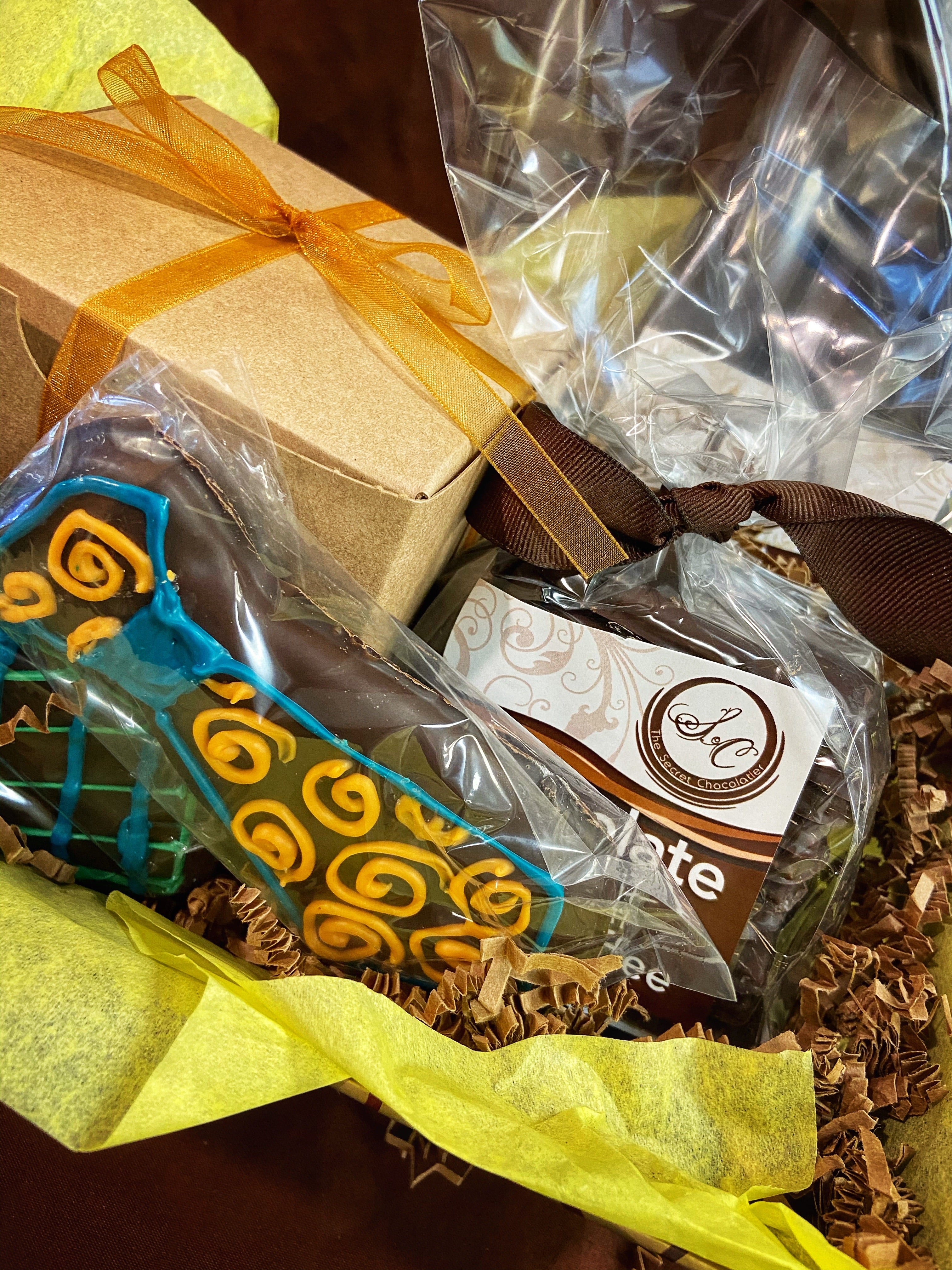Father's Day gift box detail — gold-ribbon kraft box with a blue-and-yellow-striped chocolate tie cookie and TSC-labeled cellophane pack.