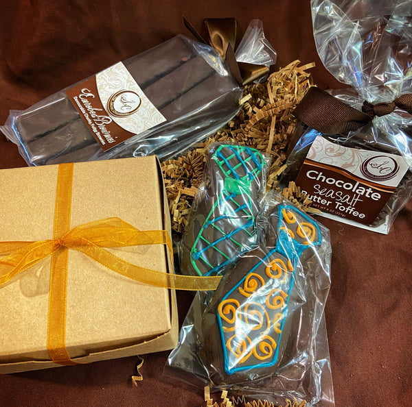 Father's Day chocolate gift assortment — Enrobed Brownies, Chocolate Sea Salt Butter Toffee, and chocolate tie-shaped cookies arranged with a gold-ribbon gift box.